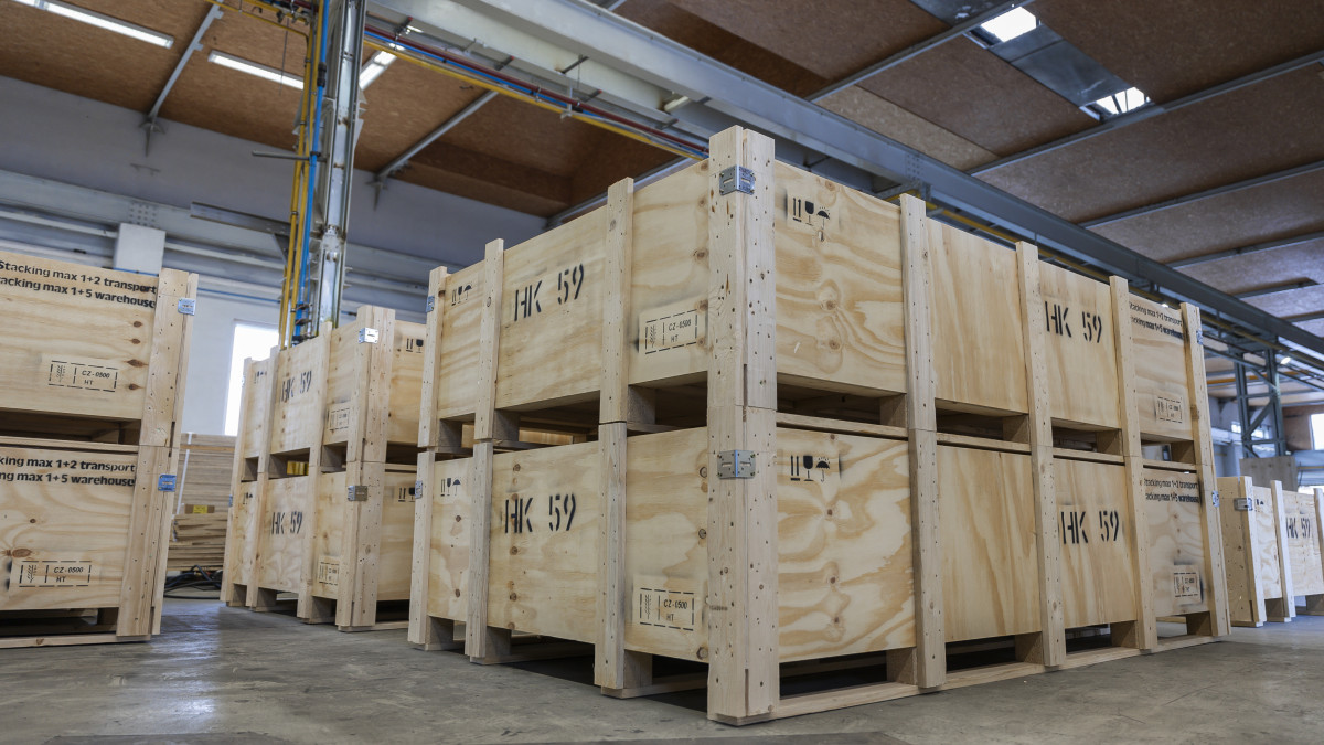 Große Lagerhalle mit mehreren gestapelten, stabilen Holzkisten aus hellem Holz mit der Aufschrift HK 59