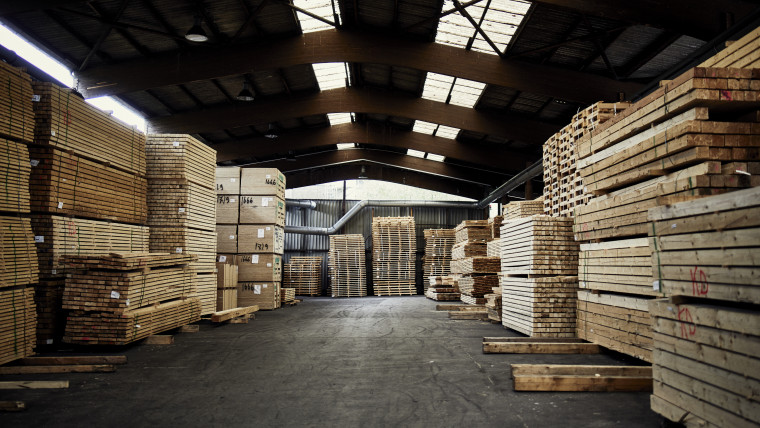 Eine Lagerhalle, wo Holzbalken gestapelt sind
