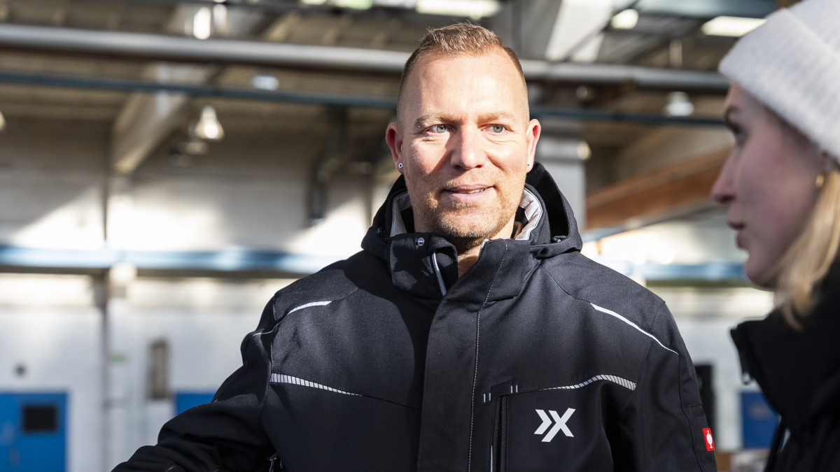 Zwei Personen stehen in einer Lagerhalle. Die eine Person erklärt der anderen etwas.