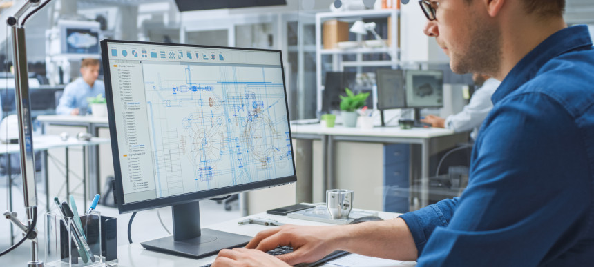 Jemand sitzt in einem Büro an einem Schreibtisch am PC und trägt etwas ein