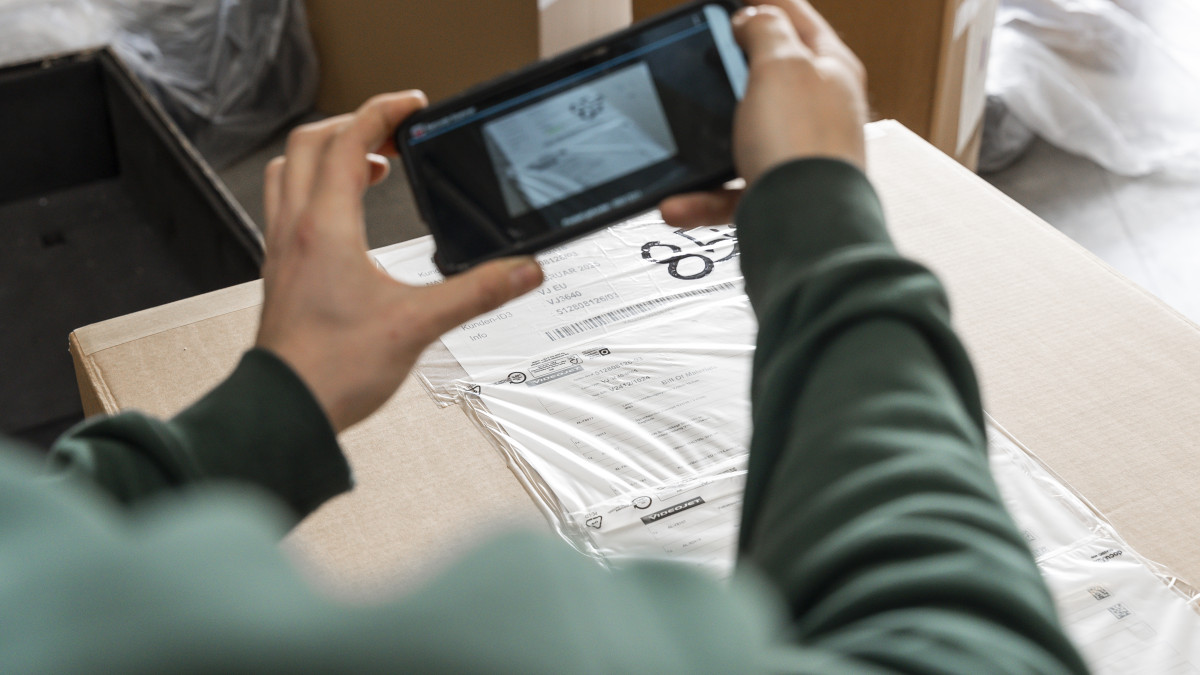 Jemand nimmt mit einem Handy eine Paketetikett auf