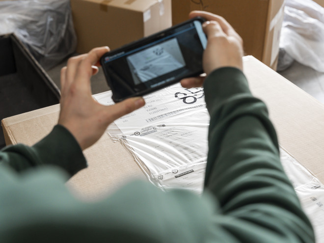 Jemand nimmt mit einem Handy eine Paketetikett auf