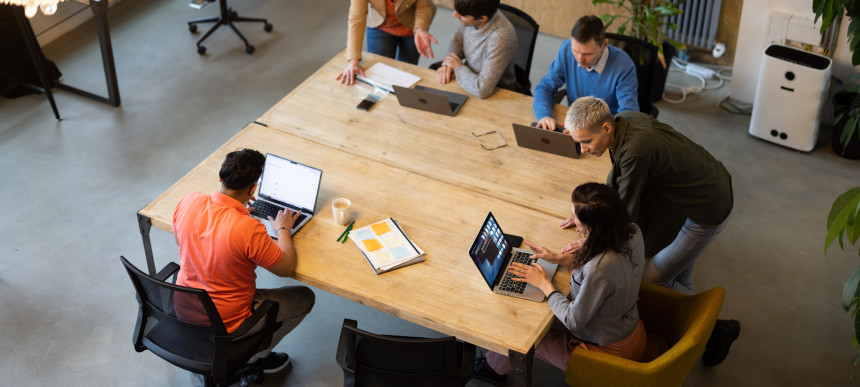 Mehrere Personen wurden von oben aufgenommen, wie sie in einem Meetingraum an einem Tisch sitzen