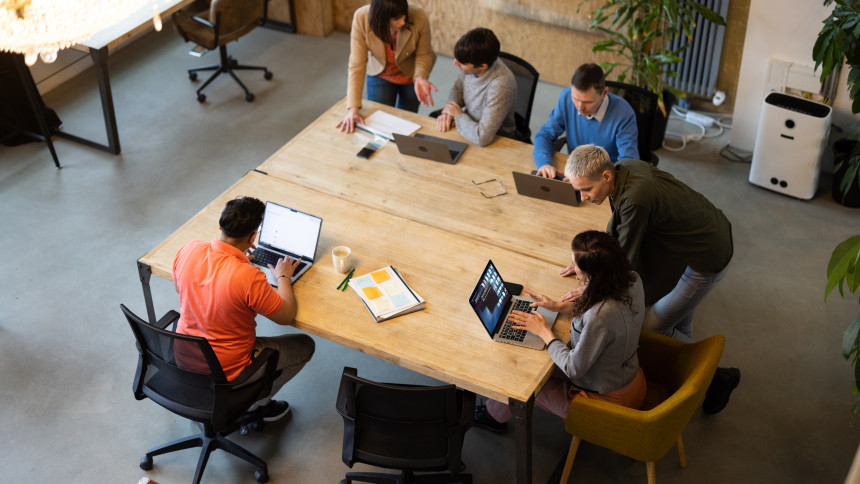 Mehrere Personen wurden von oben aufgenommen, wie sie in einem Meetingraum an einem Tisch sitzen