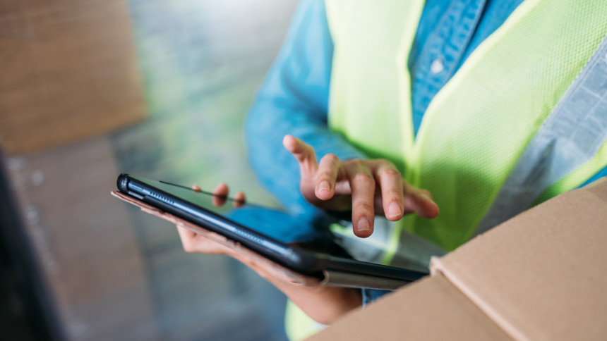 Jemand mit einer Warnweste tippt etwas auf ein Tablet ein