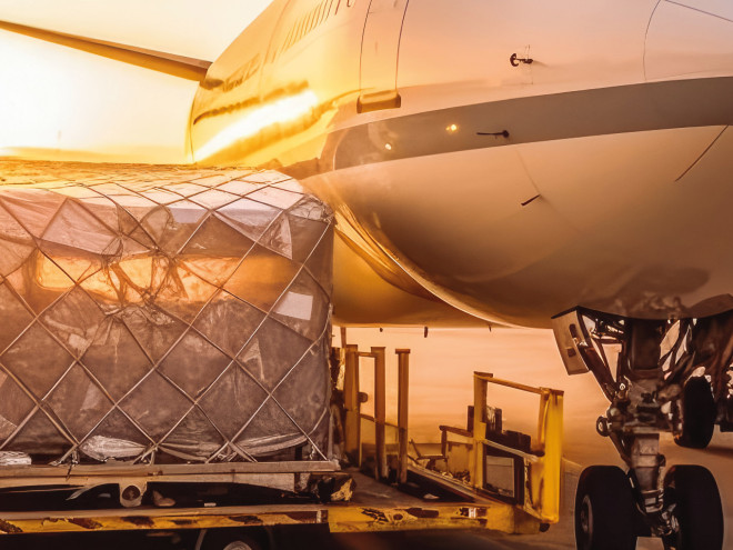 Neben einem Flugzeug steht Luftfracht, die verladen wird