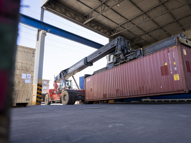 Ein großer Container wird von einem Greifstapler gegriffen.