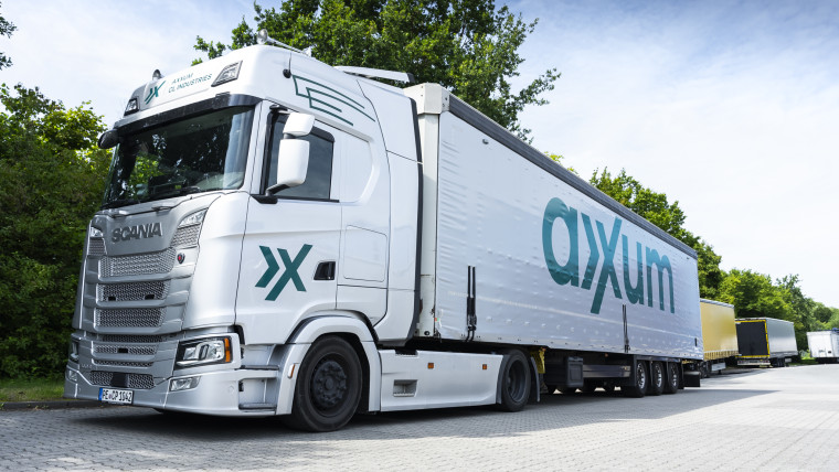 Ein großer Lastwagen mit dem AXXUM Logo auf der Seite.