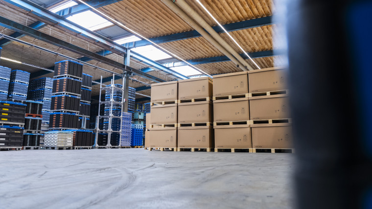 Ein großes Lager mit vielen gestapelten Kisten und Paletten, die den Raum ausfüllen.
