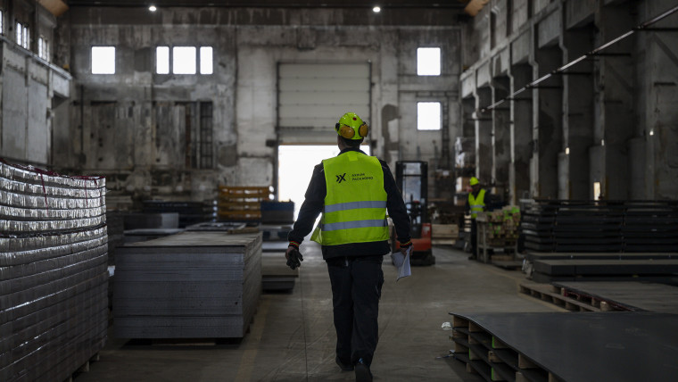 Ein Mann in gelber Sicherheitsweste läuft durch ein großes Lager.