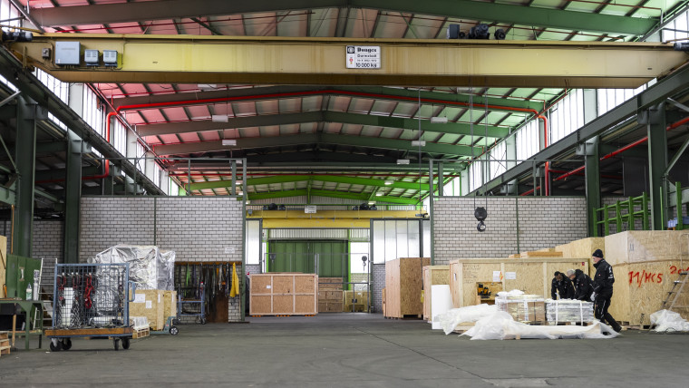 Ein Lagerhaus mit vielen Kisten und einem Mann, der zwischen den Regalen umhergeht.