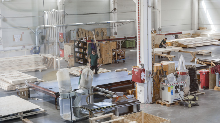 In einem großen Lagerhaus arbeiten Mitarbeiter an der Herstellung von Holzverpackungen