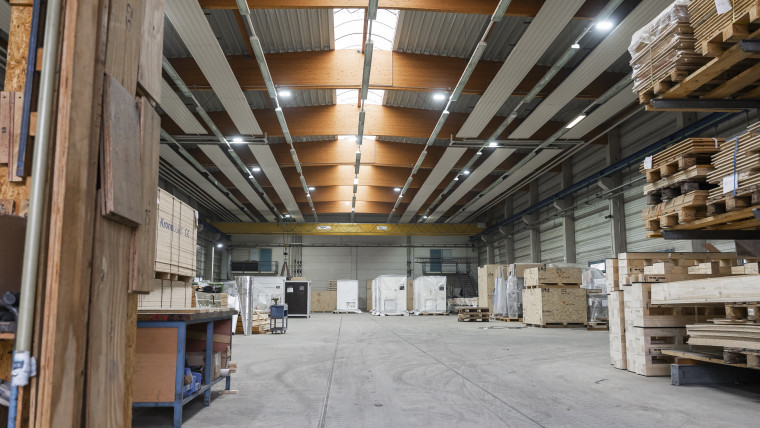 Innenansicht eines Lagerhauses mit vielen Holzpaletten und Regalen, die die Lagerfläche füllen.