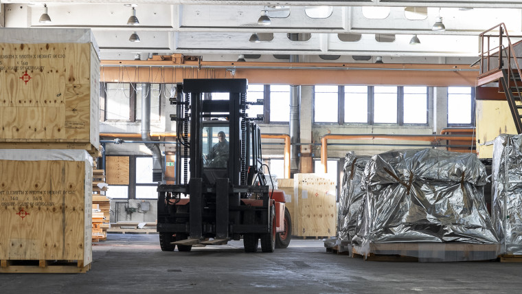Ein Gabelstapler steht in einem Lager zwischen Kisten und Paletten.