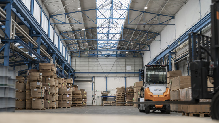 Ein Gabelstapler bewegt sich durch eine Lagerhalle, um Materialien zu lagern.