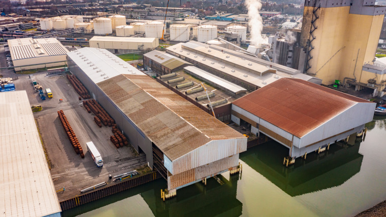 Übersichtliche Luftaufnahme einer Fabrik, die an einem Fluss liegt.