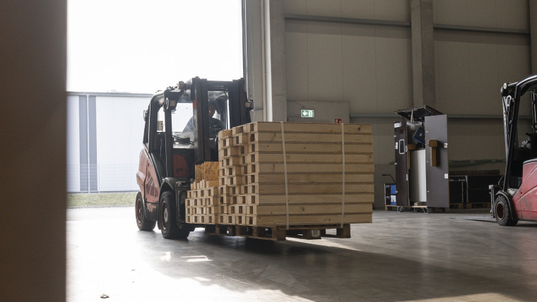 Ein Gabelstapler hebt eine Ladung Holz auf einem Lagerplatz.