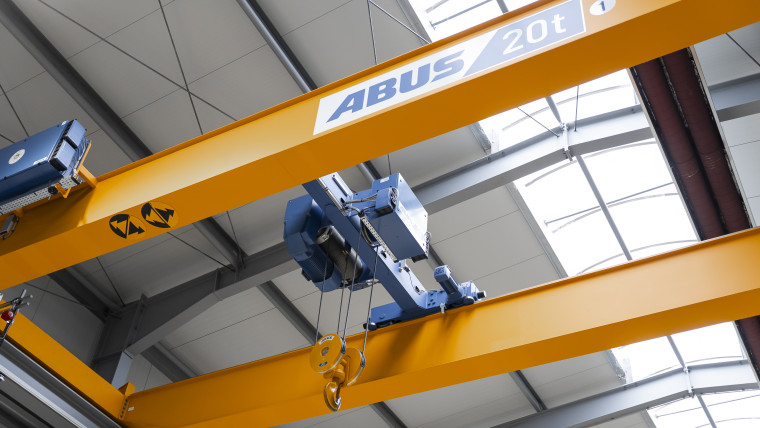 Gelber Hallenkran mit der Aufschrift ABUS 20t an der Decke einer Industriehalle