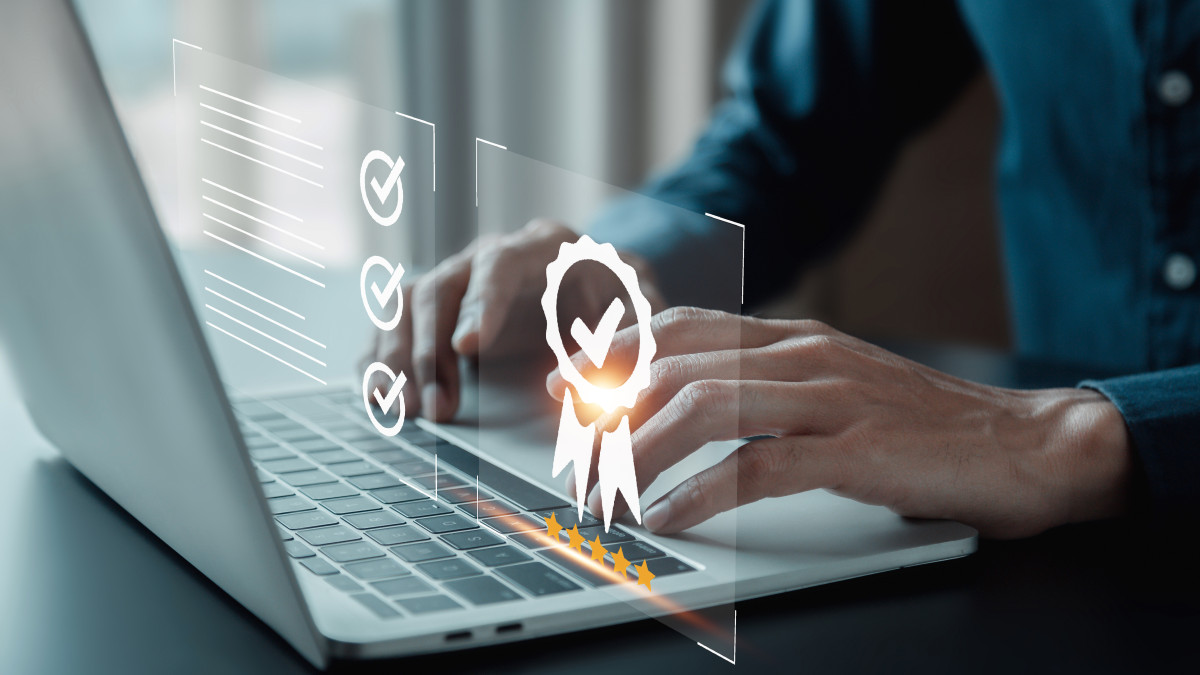 Mann nutzt einen Laptop, während ein Zertifikat und ein Auszeichnungssymbol neben ihm sichtbar sind.